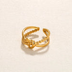 Gold knot adjustable open ring on textured cream paper with warm white background