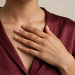 Hand on chest in wine satin V-neck blouse wearing gold knot adjustable open ring