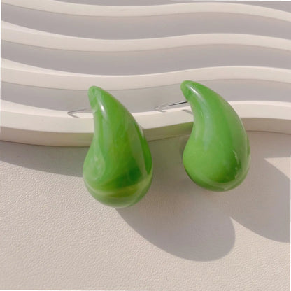 Two glossy green drop-shaped earrings displayed against a textured white background, highlighting their vibrant color and smooth finish.