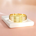 Bracelet on geometric prop with peach color gradient in the background.