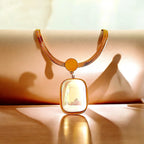 An 18K gold-plated stainless steel pendant necklace with an opal white stone centerpiece, displayed against a soft, warm background.