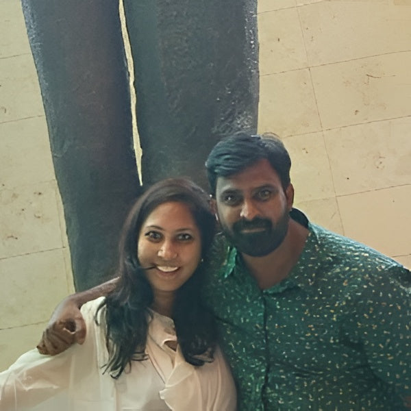 Two people posing in front of a large sculpture.