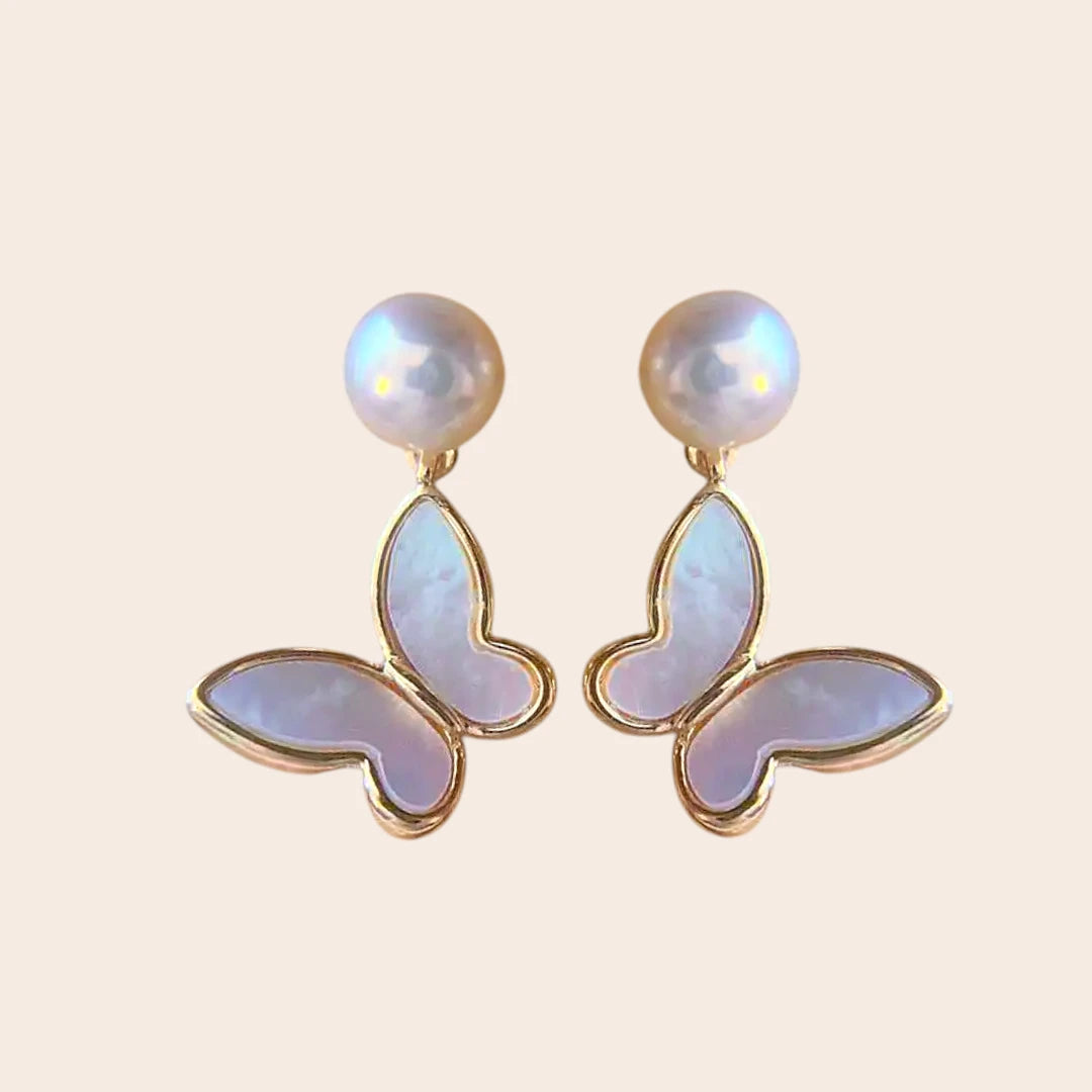 Delicate butterfly earrings featuring iridescent wings and pearl tops, set in gold for an elegant, whimsical touch.