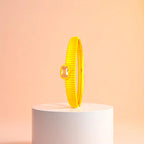 Bracelet displayed on a white pedestal against a soft peach background.