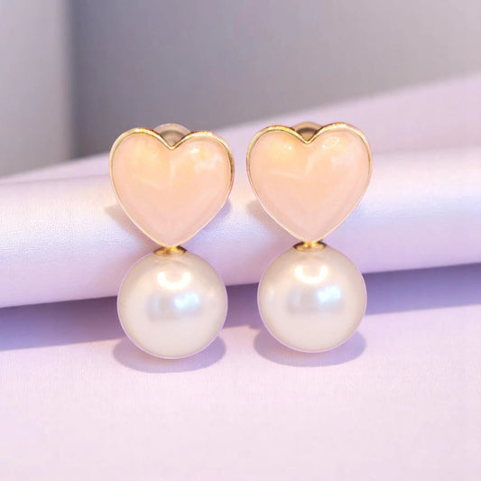 Heart-shaped earrings with pastel pink enamel tops and white pearl drops, set against a soft, elegant backdrop.