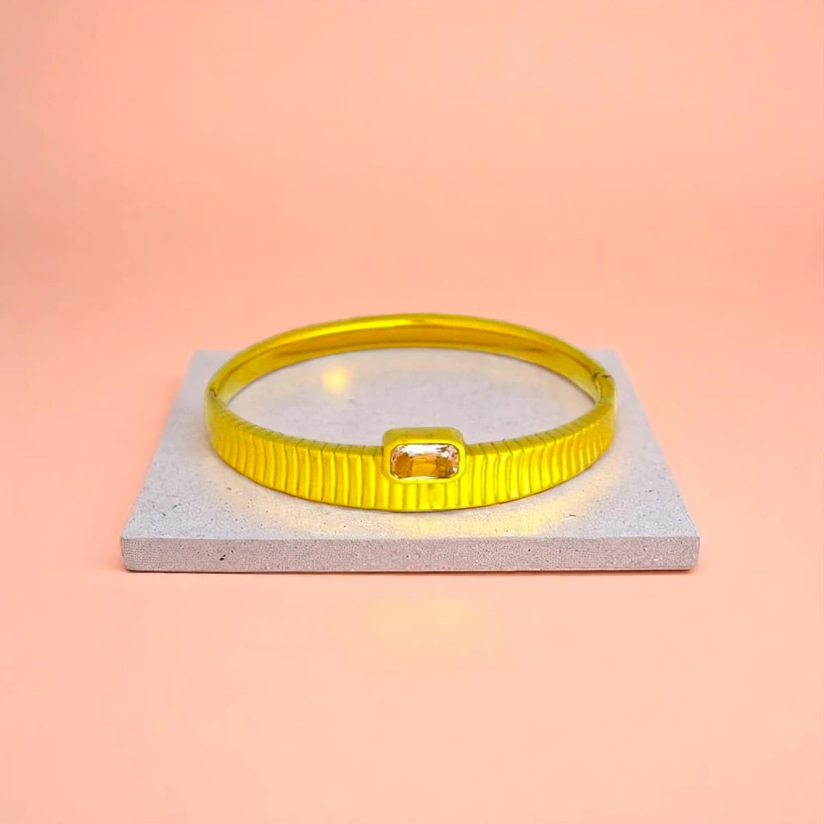 Bracelet displayed on a light-colored travertine stone slab with a peach-colored gradient in the background.