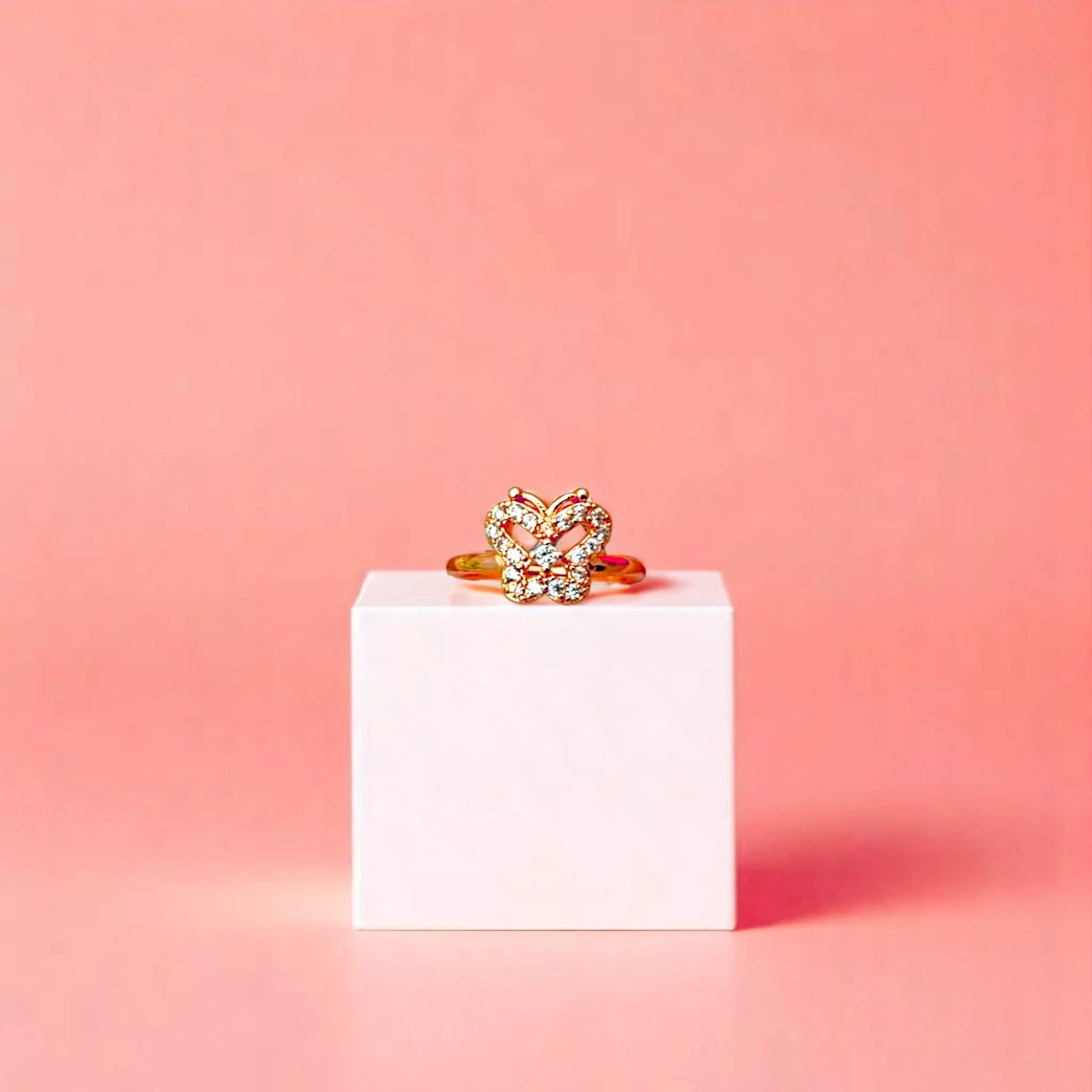 Ring on a white cube geometric prop with a peach color gradient in the background.