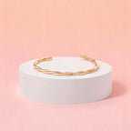 Bracelet on geometric prop with peach color gradient in the background.