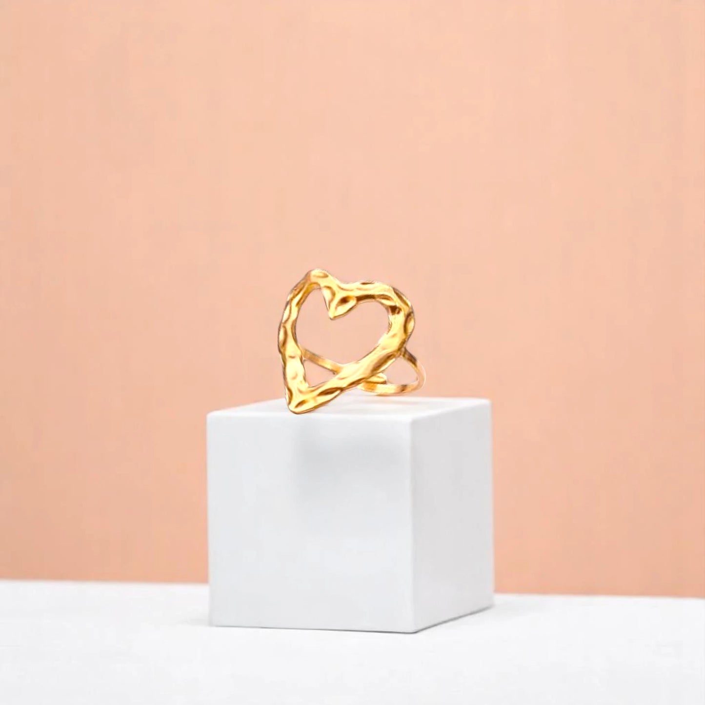 Ring on a white cube geometric prop with a peach color gradient in the background.