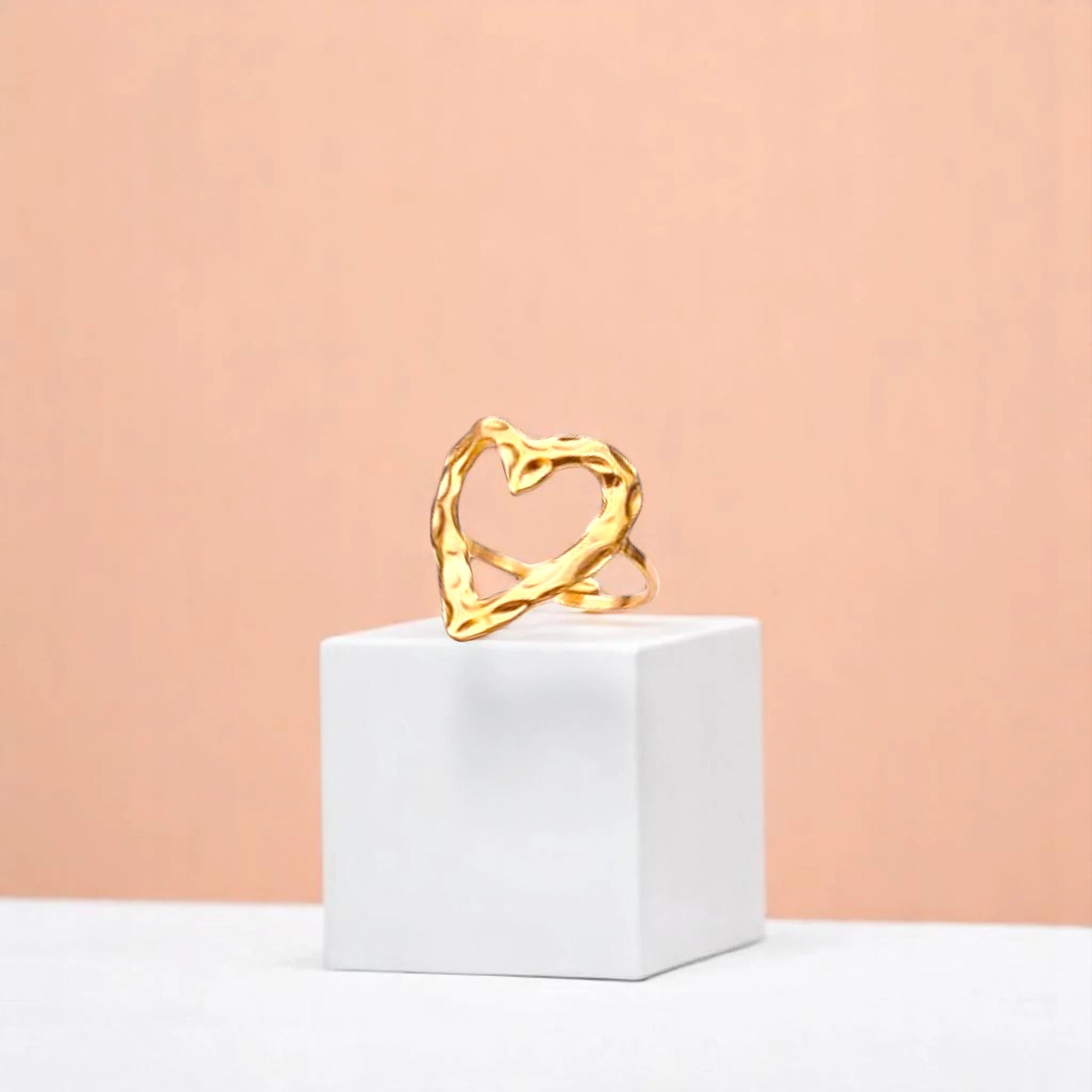Ring on a white cube geometric prop with a peach color gradient in the background.