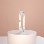 Bracelet on geometric prop with peach color gradient in the background.