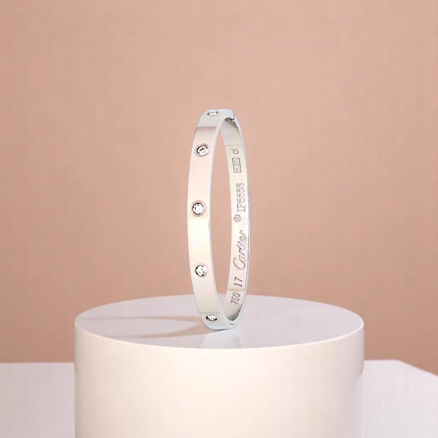 Bracelet on geometric prop with peach color gradient in the background.