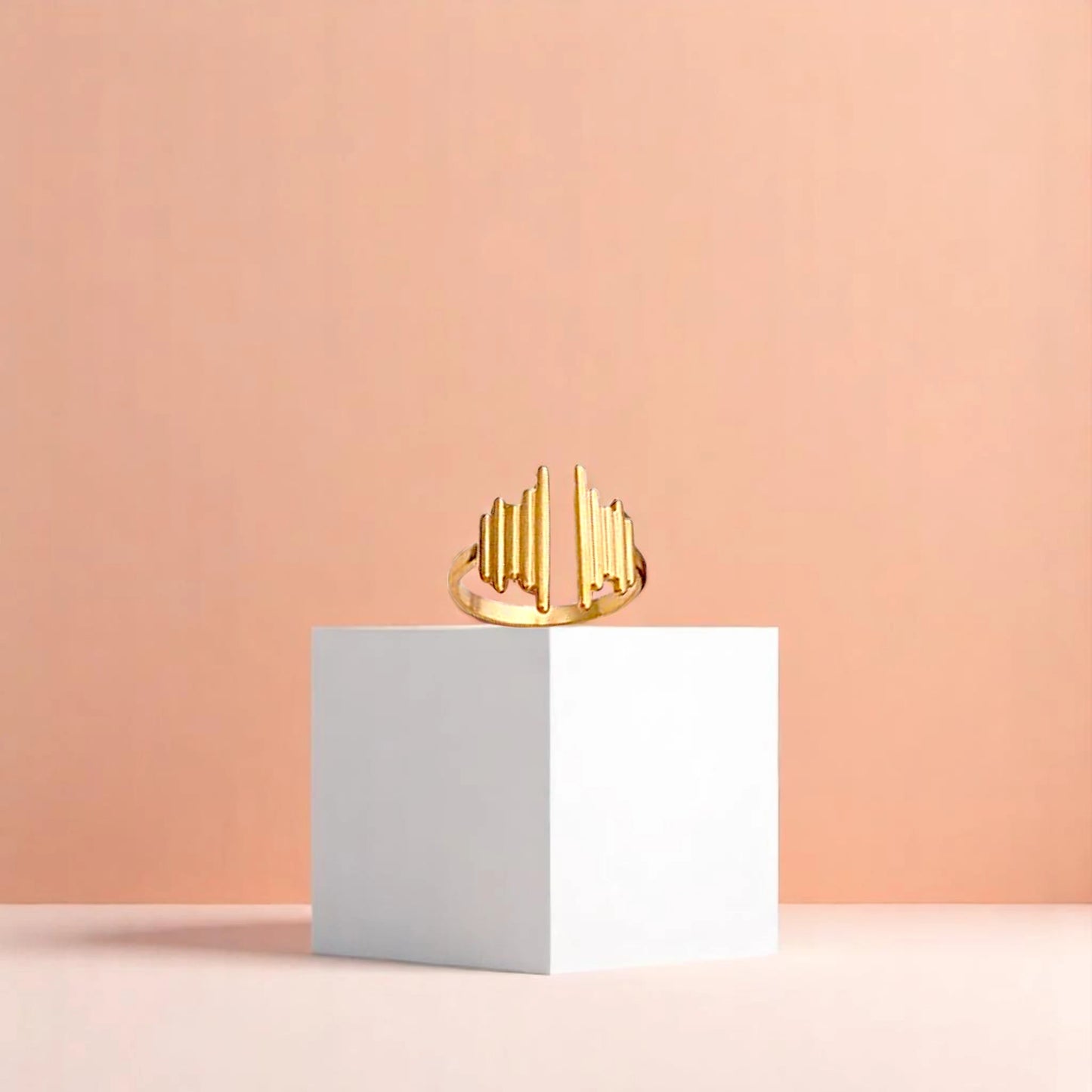 Ring on a white cube geometric prop with a peach color gradient in the background.