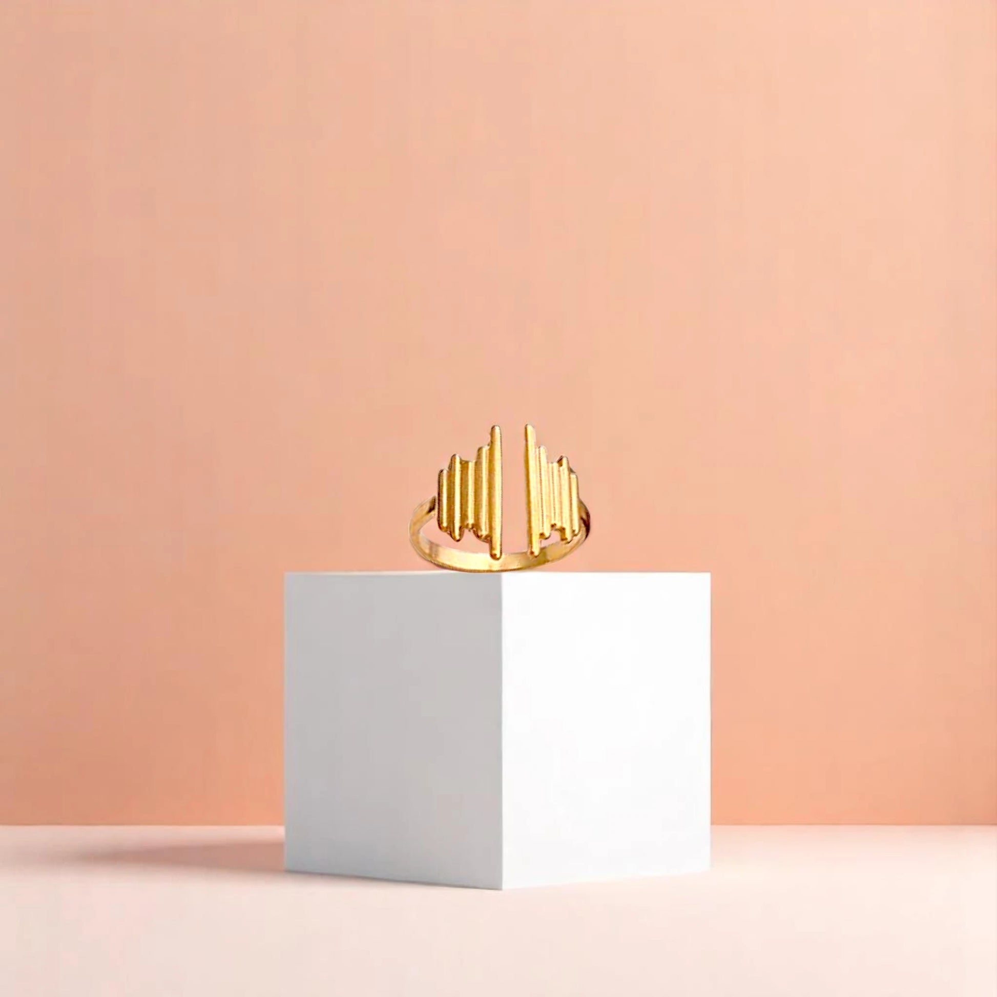 Ring on a white cube geometric prop with a peach color gradient in the background.