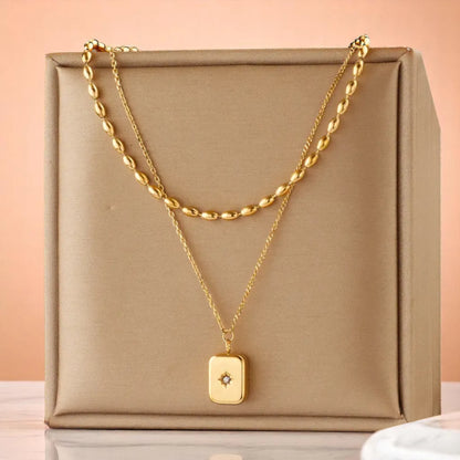 A necklace resting on a beige silk fabric jewelry box with a peach background.
