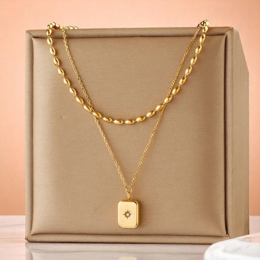 A necklace resting on a beige silk fabric jewelry box with a peach background.
