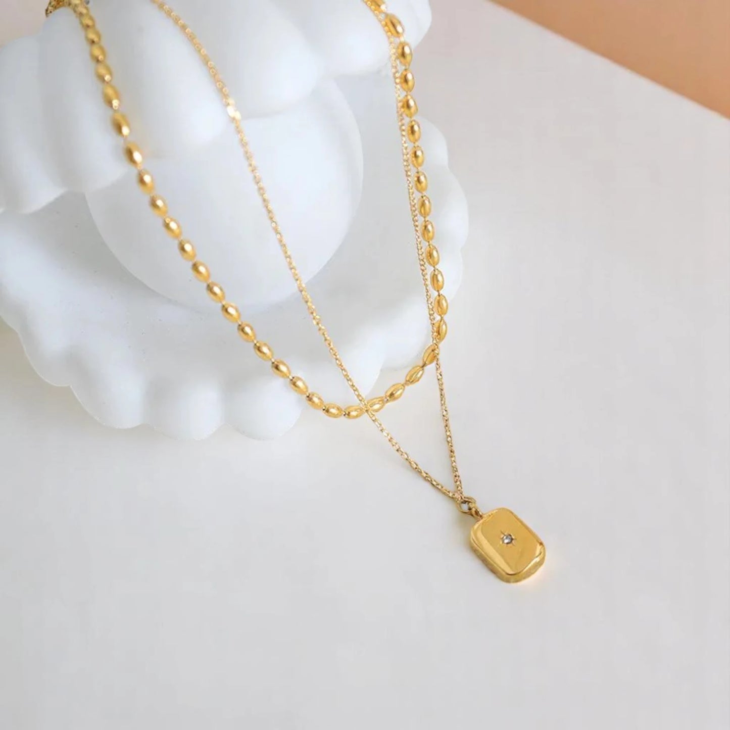 Necklace on a white seashell prop.