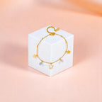 Anklet on geometric prop with peach color gradient in the background.