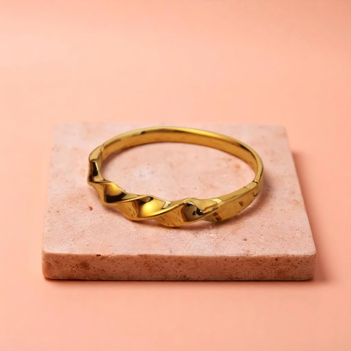 Bracelet displayed on a light-colored travertine stone slab with a peach-colored gradient in the background.