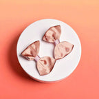 Two brown bows on a white acrylic pedestal with light background
