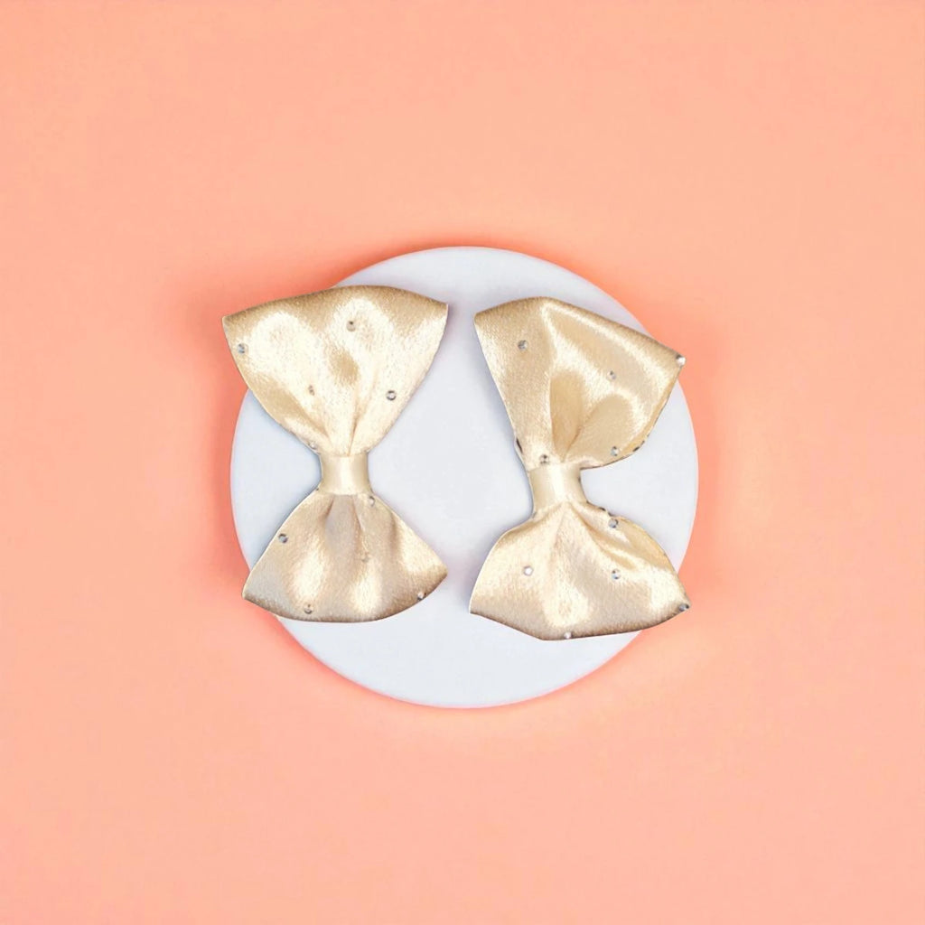 Two beige bows on a white acrylic pedestal with light background