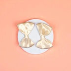 Two beige bows on a white acrylic pedestal with light background
