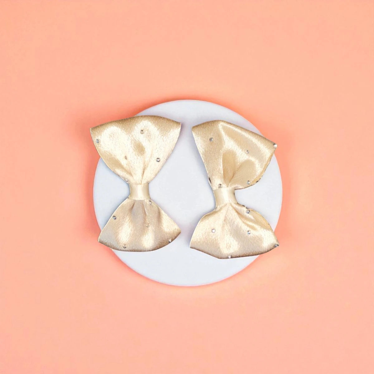 Two beige bows on a white acrylic pedestal with light background