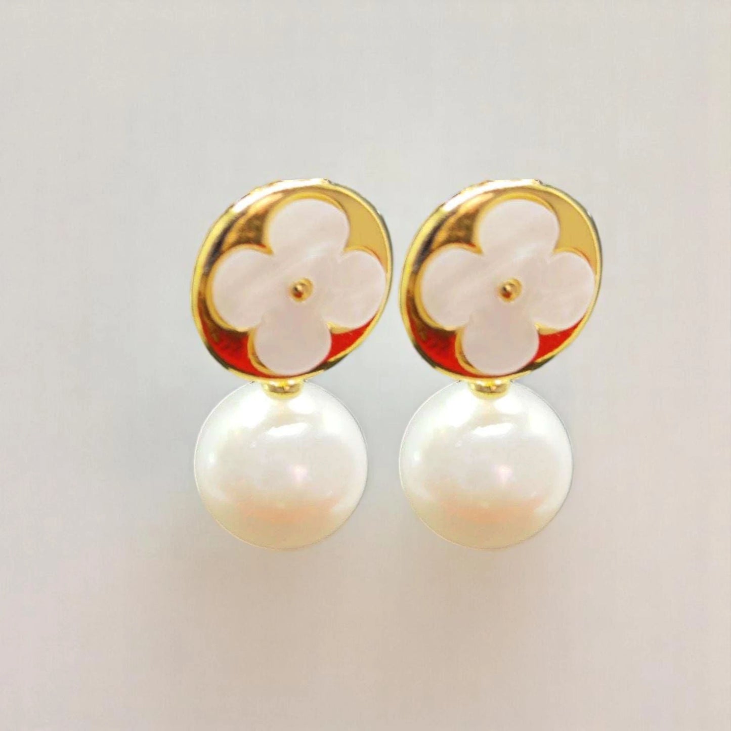 Elegant gold and white pearl earrings featuring a floral design with a glossy finish. Perfect for any occasion.