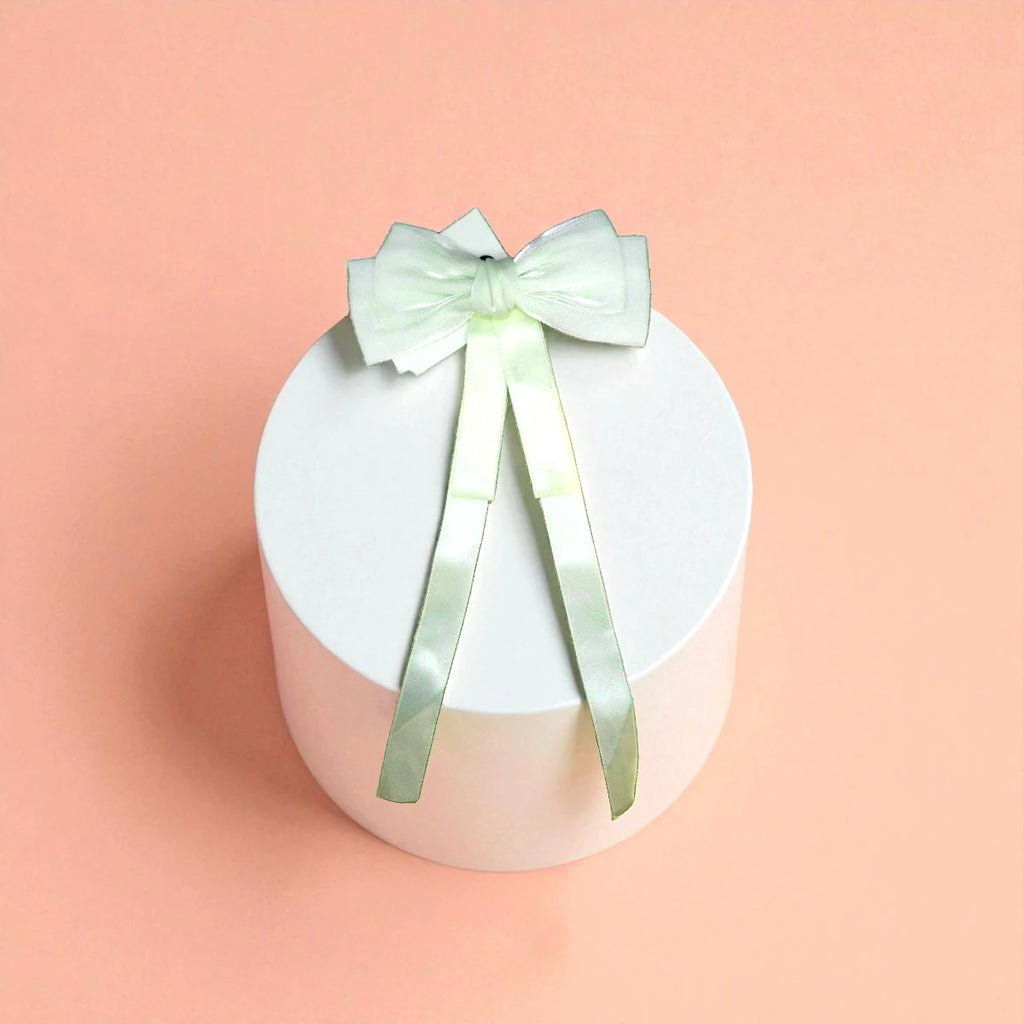 Round white acrylic pedestal with a White bow on a light background