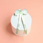 Round white acrylic pedestal with a White bow on a light background