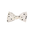 White bow tie with black polka dots on a white background