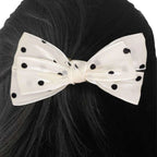 White bow hair clip with black polka dots on a person's hair