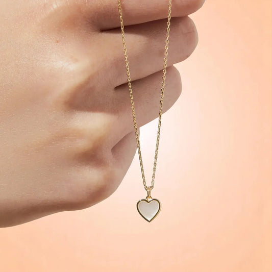 Model holding a necklace with a peach-toned gradient background.